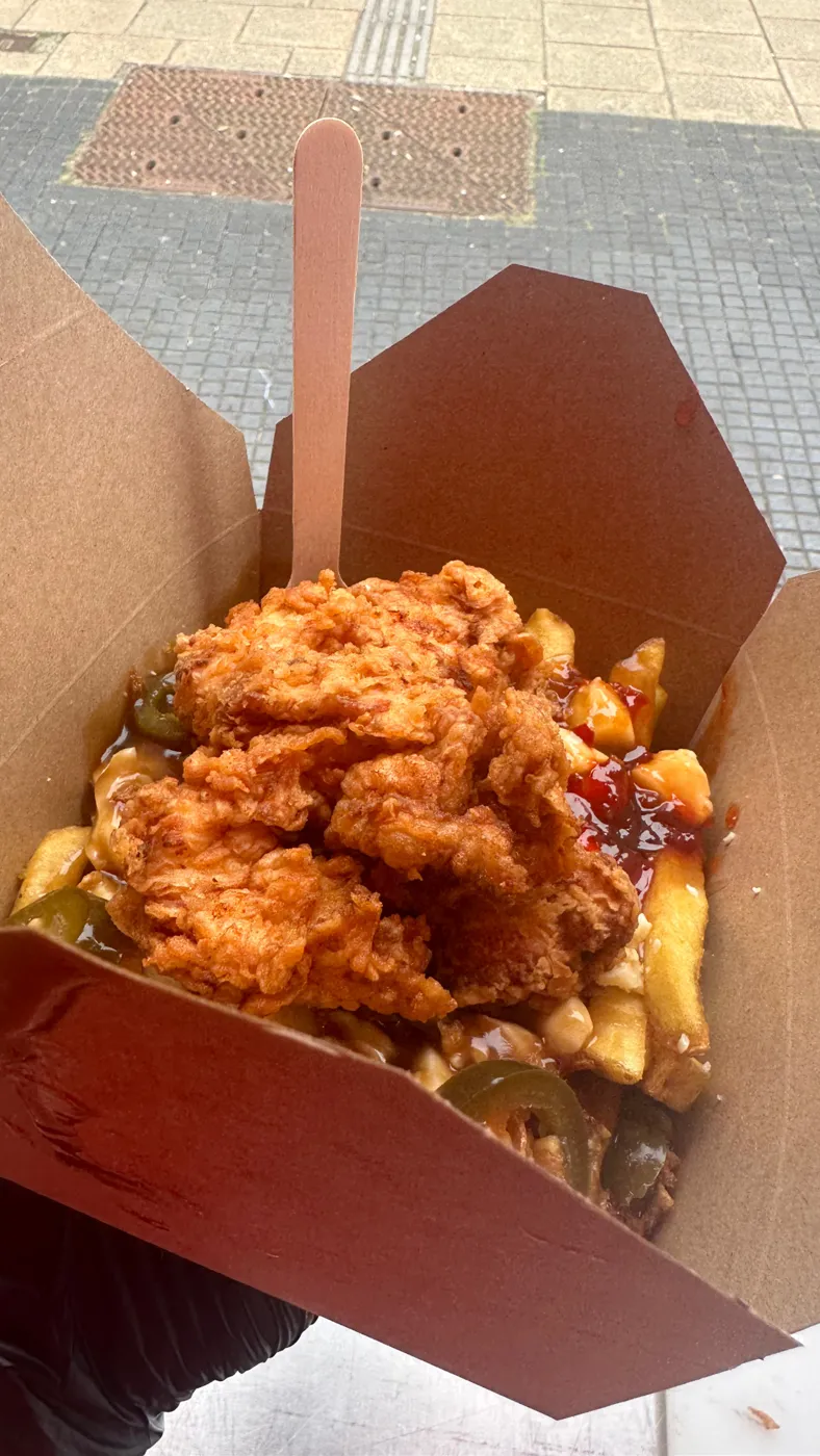 A box of fried chicken poutine with a wooden fork