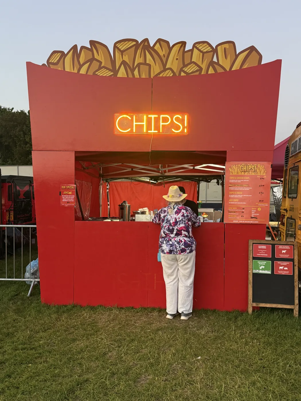 A customer ordering at the CHIPS! counter under the neon sign