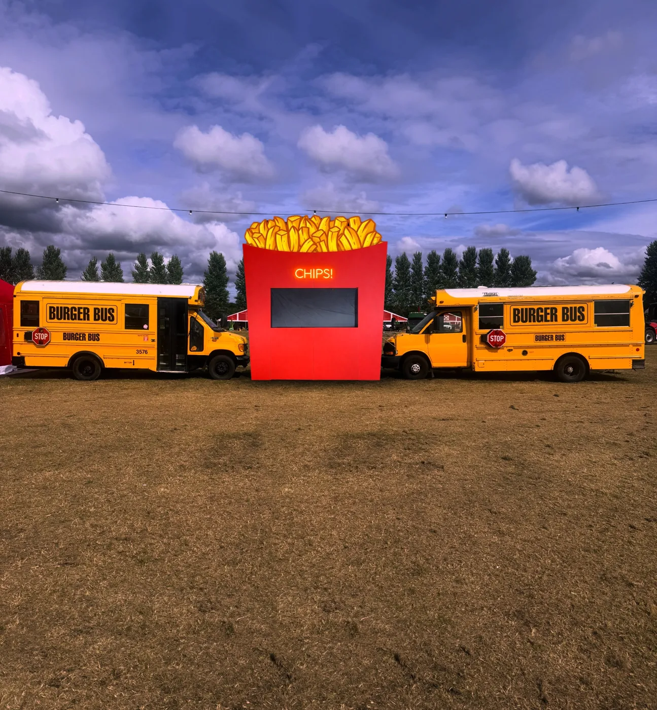 The CHIPS! stall between two yellow Burger Buses on a festival field